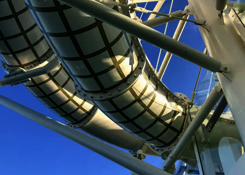 Rutsche mit weißen Segmenten und grünem Rautenmuster vor blauem Himmel.