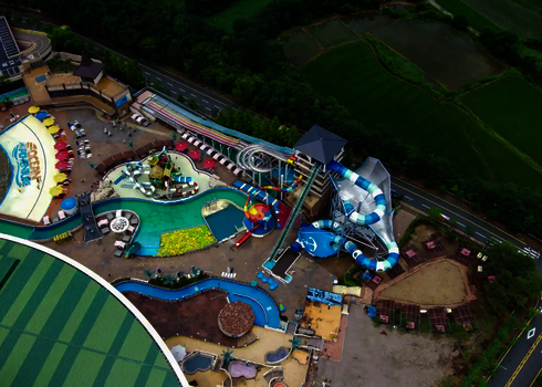 Overall view of the water park with raft conveyor, slide landscape, and green surroundings.