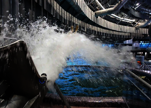 Großer Wasserschwall der aus einem Cannonball kommt, mit Blick auf ein Hallenbad.