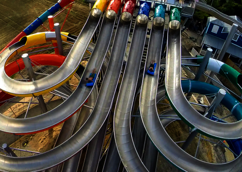 Luftaufnahme der Wasserrutsche Matracer mit bunten Mattenrutschbahnen und Spiralröhren.