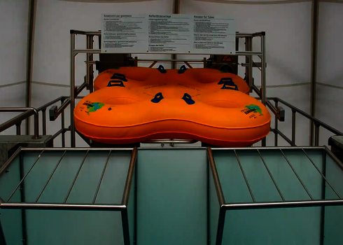 A large four-person slide raft is located at the upper discharge point of the tire transport system.