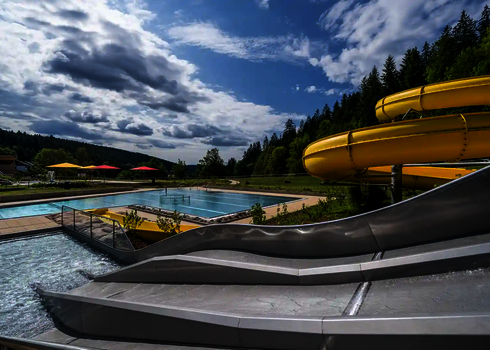 Outdooransicht der Trio-Slide mit drei Rutschbahnen neben einem Freibad.