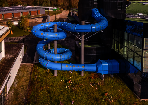 Weitblick auf eine große blaue Wasserrutsche mit gepunkteten Tageslichteffekten.