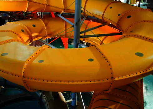 Gelbe Family Twister Wasserrutsche mit engen Kurven im Innenbereich des Wasserparks.