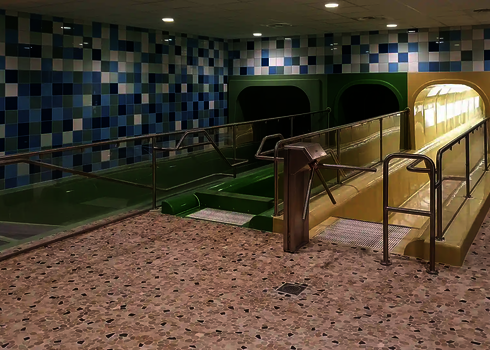 Three enclosed water slides with separate run-outs and handrails in an indoor pool.