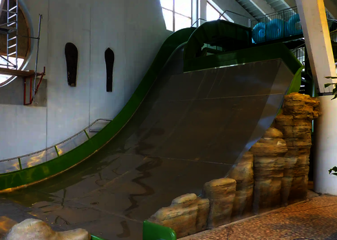 Grüne Sidewinder im Innenbereich mit Felsdeko und Zugangstreppe.