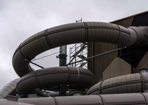 Blick von außen auf eine weiße Wasserrutsche außerhalb eines Gebäudes.