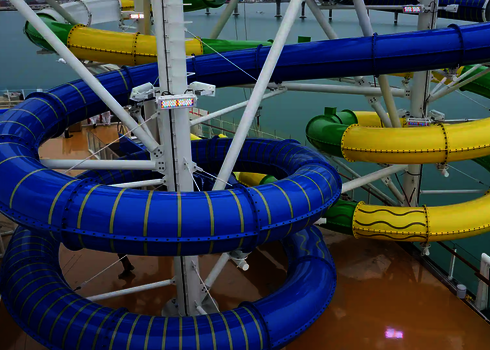 Blaue und gelbe Röhrenrutschen mit glatter Außenfläche auf einem Außendeck am Hafen.