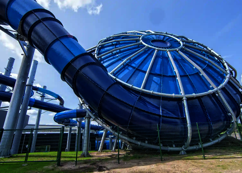Blauer Cyclone mit sichtbarem Trichtereingang und Röhrenrutsche auf grünem Gelände.