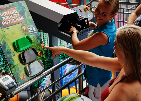 Zwei Frauen stehen vor einem Auswahl-Pad für Virtual Reality Wasserrutschen in einem Schwimmbad.