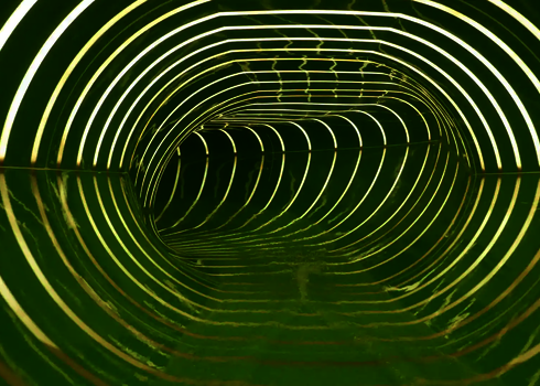 Innenansicht einer grünen Wasserrutsche mit gestreiften Tageslichteffekten in gelb.