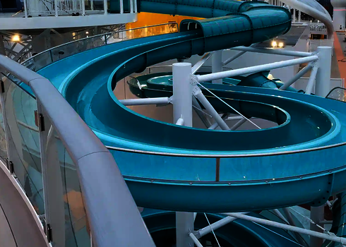 Kurvige 2-in-1 Racer Wasserrutsche mit erhöhtem Geländer und gelbem Hintergrund auf einem Kreuzfahrtschiff.