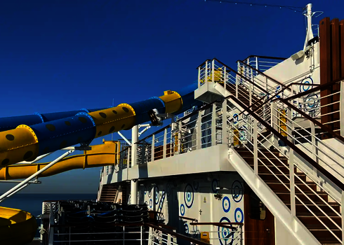 Mehrere blaue und gelbe Rutschen befinden sich an Deck eines Kreuzfahrtschiffes.