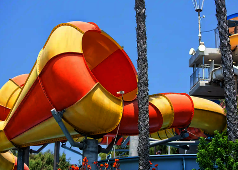 Seitlicher Blick auf die markante Trichteröffnung der Crazy Cone Rutsche mit Palmen im Vordergrund.