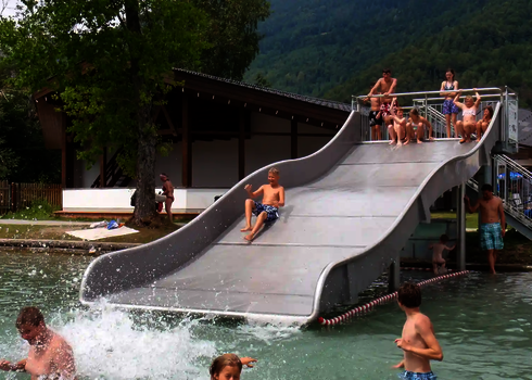 Badegäste in einem Schwimmbad und auf einer Breitwellenrutsche.