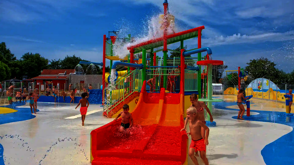 Bunter Kinderbereich mit spielenden Kindern in einem Wasserpark.