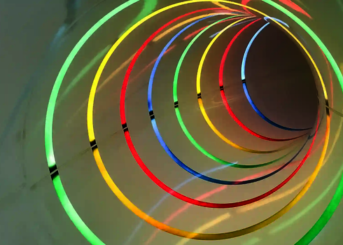 Innenansicht einer Röhrenrutsche mit bunten Lichteffekten.