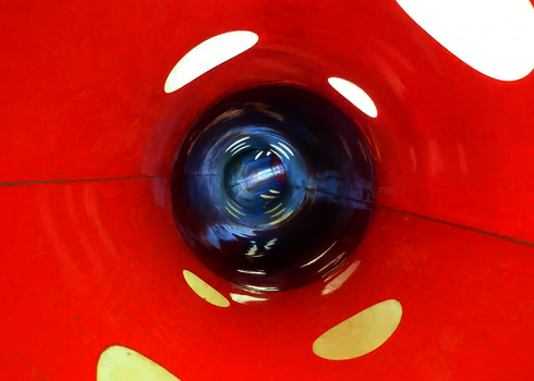 Innenansicht einer roten Wasserrutsche mit Tageslichteneffekten an den Rutschwänden.