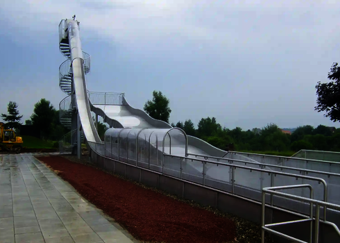 Eine Freifallrutsche und eine Breitwellenrutsche stehen nebeneinander, im Hintergrund Bauarbeiten. 