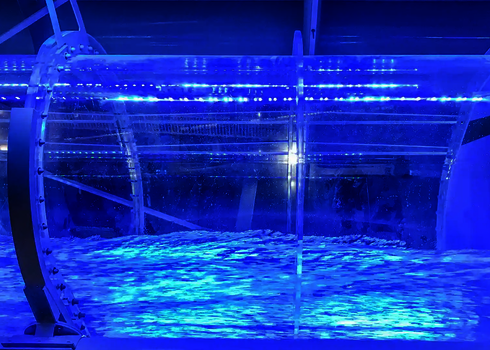 Acrylröhre mit blauer LED-Beleuchtung zeigt Wasserströmung in einer Indoor-Wasserrutsche.