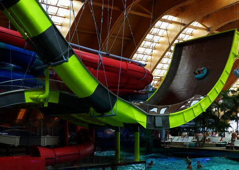 Ein Badegast fährt mit dem Reifen die Boomerang-Rutsche in einer tropischen Badewelt hinauf.