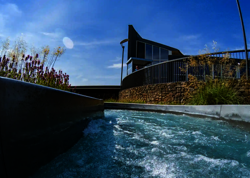 Sprudelndes Wasser strömt durch den Wildwasserfluss, umgeben von Blumen und hohen Gräsern.