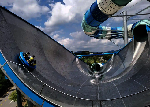 Personen in blauen Rutschreifen befinden sich auf der riesigen Urknall-Reifenrutsche unter freiem Himmel.