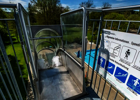 Einstiegsbereich einer Freifallrutsche mit Hinweistafel und klarer Sicht auf den Auslauf.