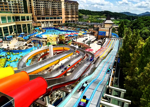 Luftaufnahme der Wasserrutsche Matracer im Wasserpark mit umliegenden Becken und Gebäuden.