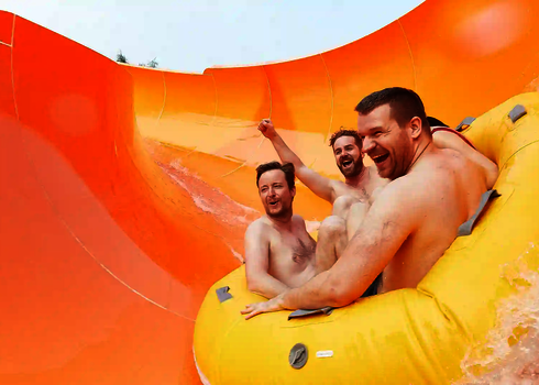 Drei Männer rutschen lachend durch den orangenen Tunnel der Reifenrutsche RR2700.