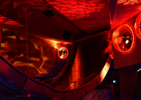 Steile Boomerang-Rampe im Indoor-Bereich mit intensiver Beleuchtung und Projektionen.