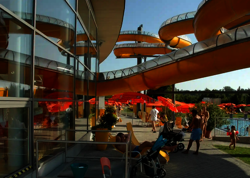 WR1040-Rutsche mit gelbem Verlauf führt durch ein Erlebnisbad mit Holzdach.