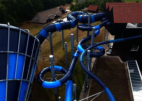 Nahaufnahme des Cyclone-Trichters mit blauer Röhrenrutsche, angrenzend an ein dunkles Gebäude.