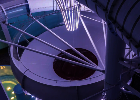 Beleuchteter Trichter einer Wasserrutsche mit violettem Zentrum und weißen Streben.