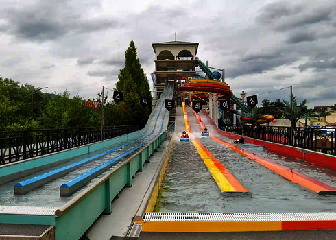 Blick auf eine Matracer Wasserrutsche mit bunten Bahnen und zwei Personen auf Rutschmatten.