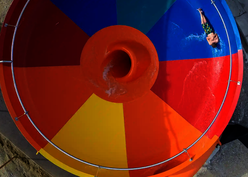 Bunte Body-Bowl-Rutsche mit rot-gelbem Trichter und Wasserstrahl im Zentrum.