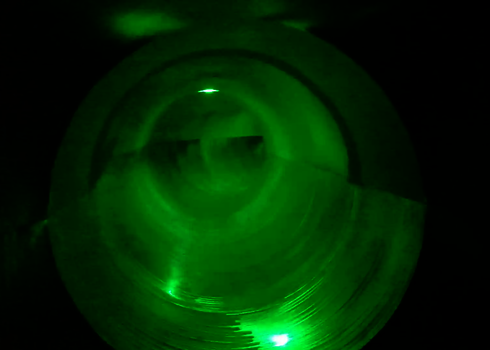 Grüner LED-Effekt in einer dunklen Rutsche mit symmetrischem Tunnelblick.