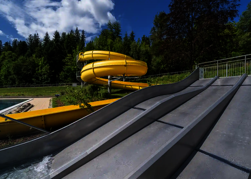 Trio-Slide endet in ein Kinderbecken, dahinter weitere Becken und Liegebereich.