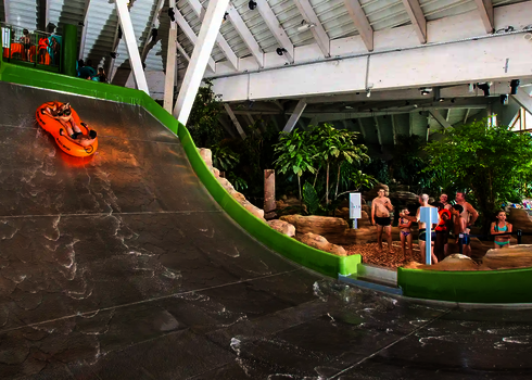 Fahrer in orangem Doppelreifen auf der Sidewinder vor wartenden Gästen.