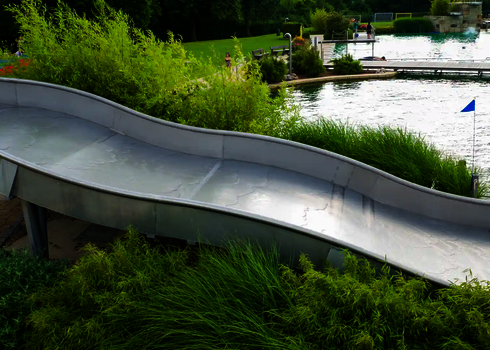 Eine Breitwellenrutsche umgehen von Sträuchern, in einem Freibad.