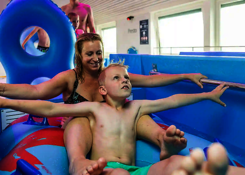 Frau mit Kind in einem Reifen beim Einstieg in eine Wasserrutsche.