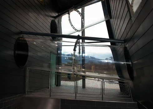 Zwei transparente Acrylröhren im Innenbereich mit Blick auf die verschneite Berglandschaft.