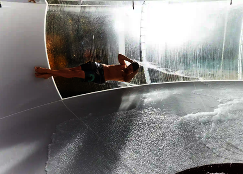 Nahansicht, wie eine Person in Badehose die Body Bowl Wasserrutsche entlangrutscht.