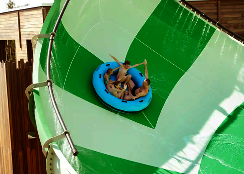 Familie fährt auf blauem Rutschreifen die steile Halfpipe der Lotus Reifenrutsche hinunter.