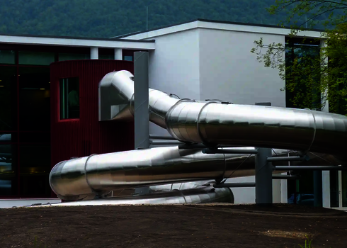 Edelstahl Wasserrutsche die aus einem Gebäude kommt.