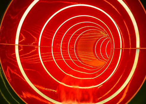 Innenansicht einer Röhrenrutsche in grün und orange mit gestreiften Tageslichteffekten.