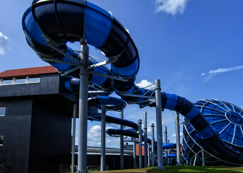 Seitenansicht einer blauen Röhrenrutsche und des Cyclone-Trichters neben einem Rutschenturm.