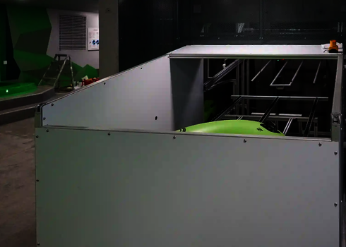 Green single tire is located in a semi-enclosed raft conveyor with metal rails.