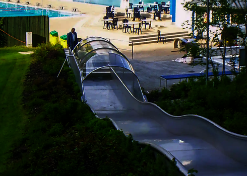 Blick von oben auf den Auslaufbereich einer Breitwellenrutsche, im Hintergrund sind Tische und Stühle.
