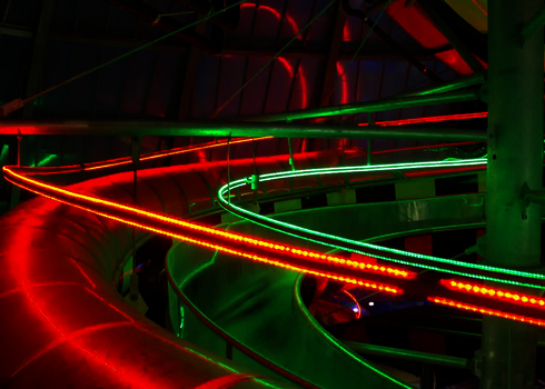 Spiralrutschen mit LED-Streifen in Rot und Grün beleuchtet, Sicht von schräg unten.